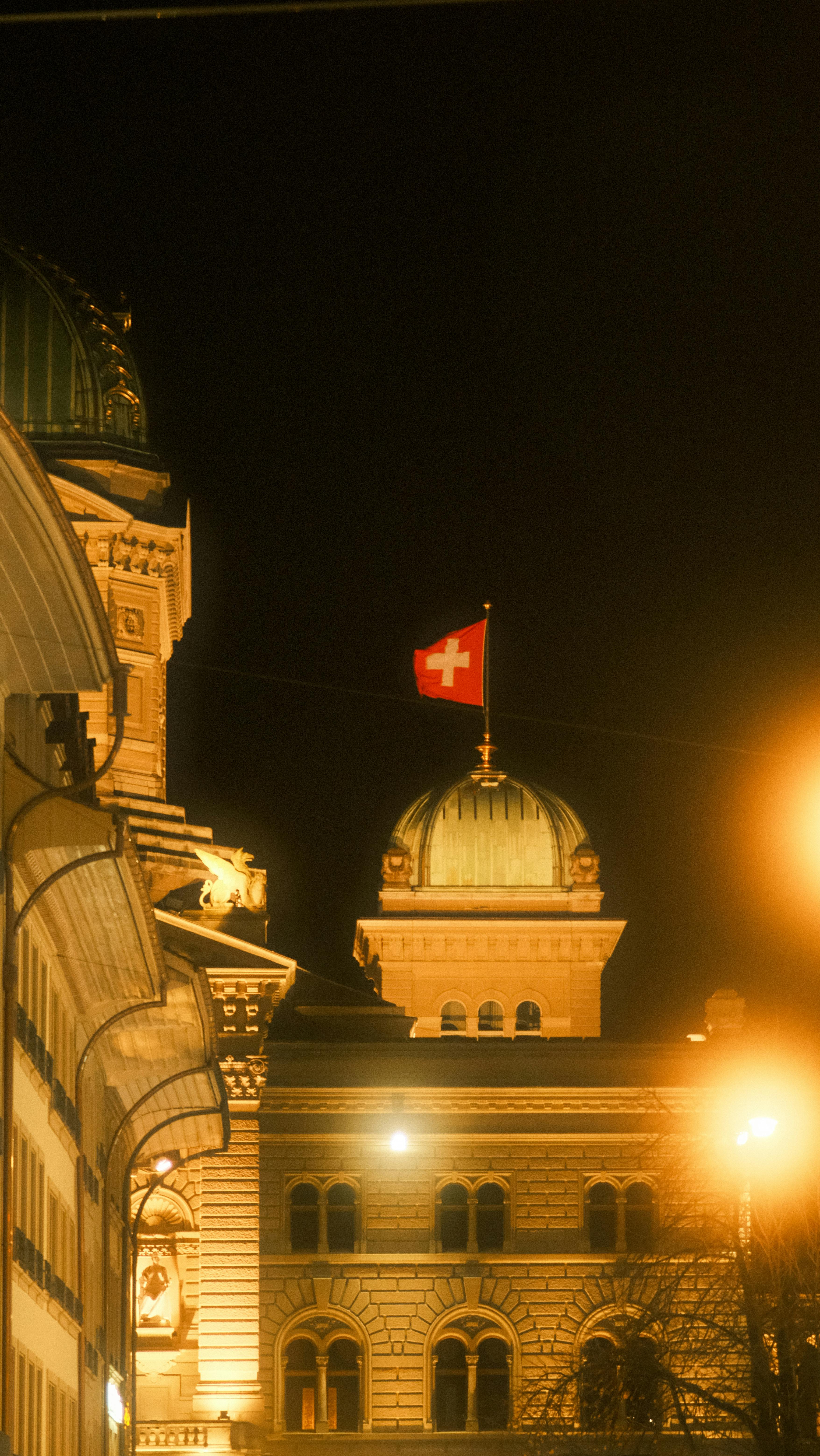 Schweizer Infrastruktur — Bundeshaus mit Schweizer Flagge bei Nacht